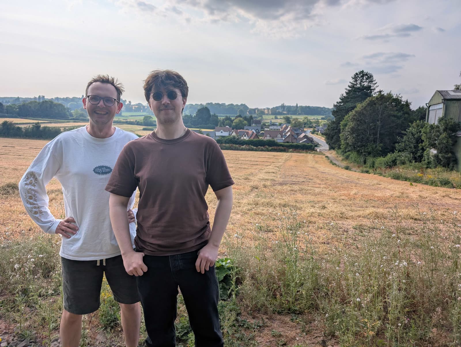 Two of the team walking through a field with a village behind them